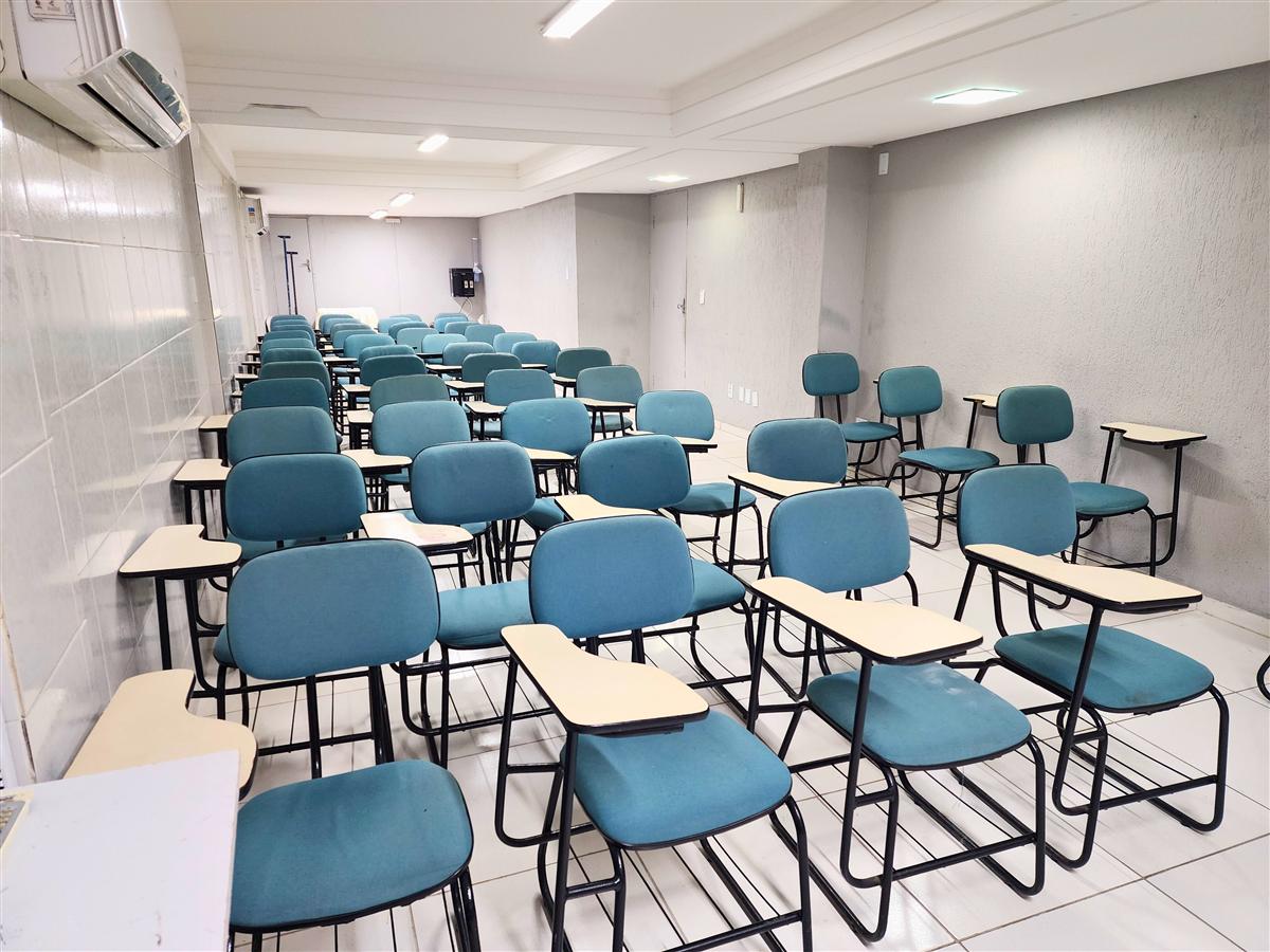 Sala de reunião do JR Hotel com cadeiras e tela de projeção